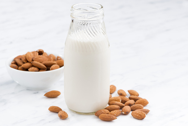 almond milk in a glass bottle on white table, closeup - Foto, afbeelding