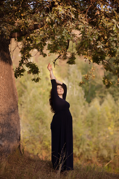 szép terhes nő egy sötét ruha szabadban - Fotó, kép