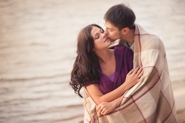 Couple amoureux sur le rivage enveloppé dans un plaid, soirée fraîche
. - Photo, image