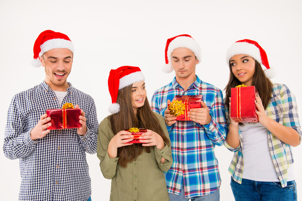 Young cheerful people in santa hats holding presents - Fotó, kép