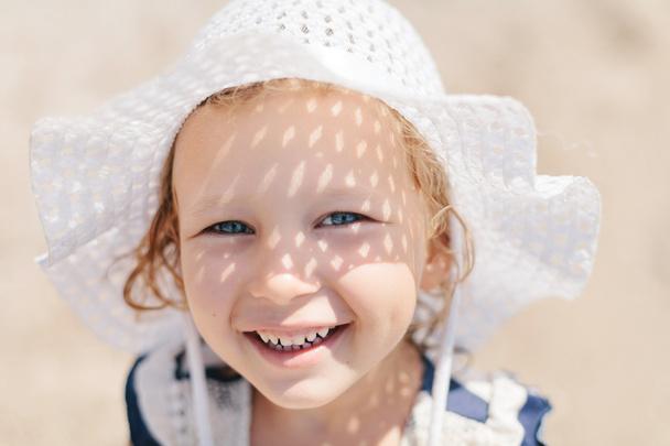 Adorable happy smiling little girl with curly hair on beach vaca - Φωτογραφία, εικόνα