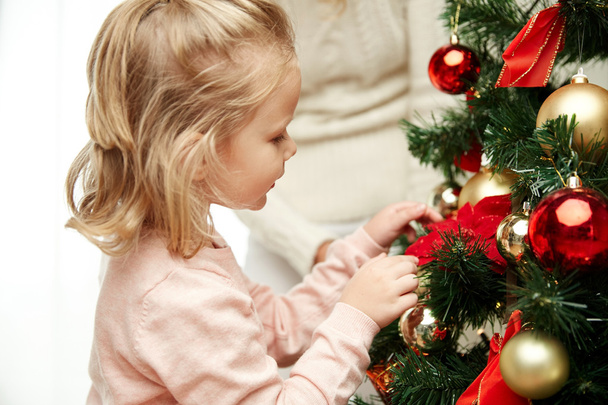 little girl decorating christmas tree at home - Foto, Imagen