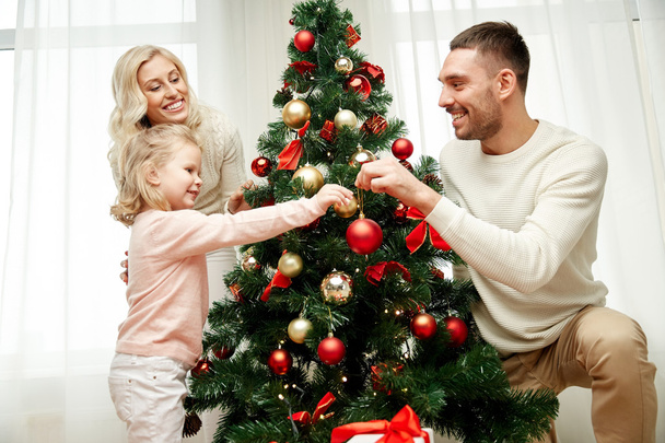 happy family decorating christmas tree at home - Foto, afbeelding