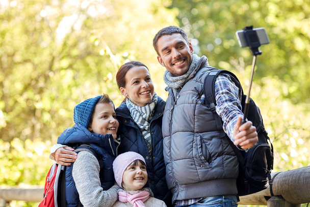 happy family with smartphone selfie stick in woods - Foto, immagini