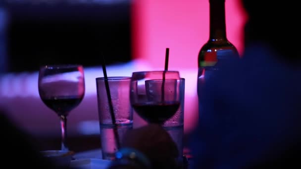 Mensen drinken wijn bij bar met koele verlichting. - Video