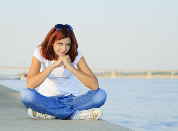 Jovem mulher sentada perto do rio no dia de verão
 - Foto, Imagem