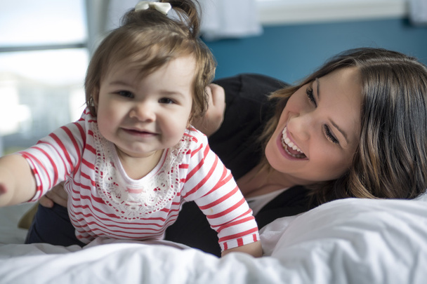 Mother and baby playing and smiling on the bedroom - Foto, Imagen