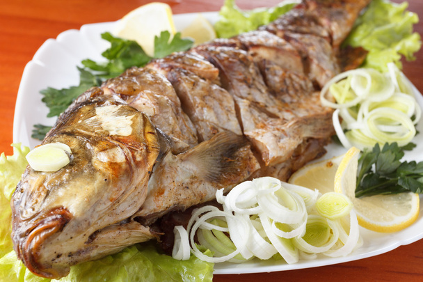 Roasted carp fish with vegetables entirely. Traditional Christmas menu. - 写真・画像