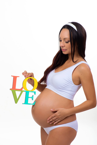 Label "Love" in the hands of pregnant woman isolated on vertical white background - Foto, imagen