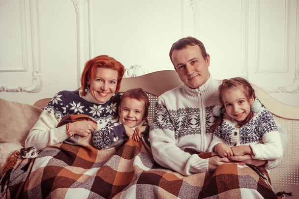 Όμορφη οικογένεια σε το πουλόβερ είναι για τον στον καναπέ κάτω από το - Φωτογραφία, εικόνα