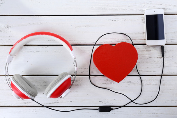Sluchátka se srdcem a telefon na dřevěné pozadí - Fotografie, Obrázek