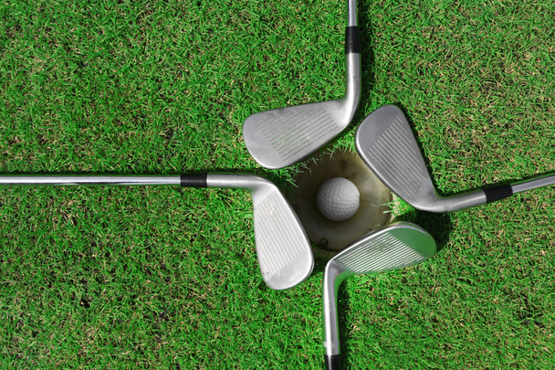 Golf ball in cup with clubs - Φωτογραφία, εικόνα