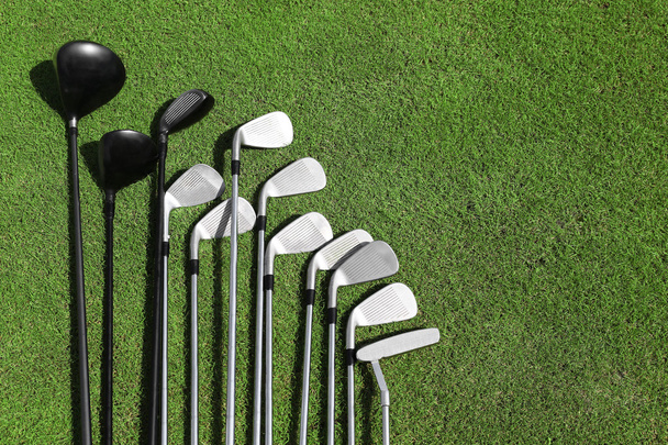 Different golf clubs in a row on a green grass - Fotó, kép