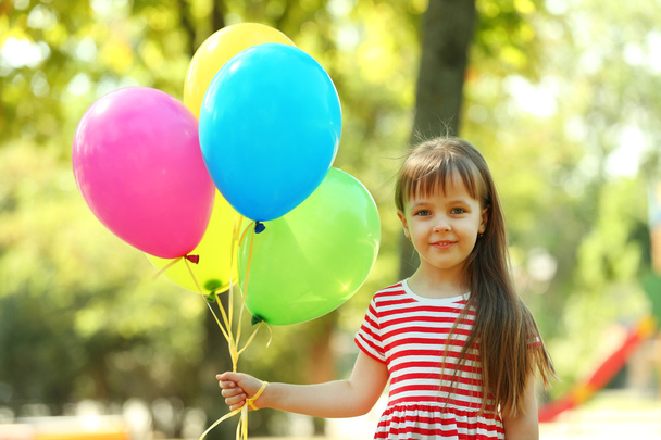 Little girl with balloons in the park - 写真・画像