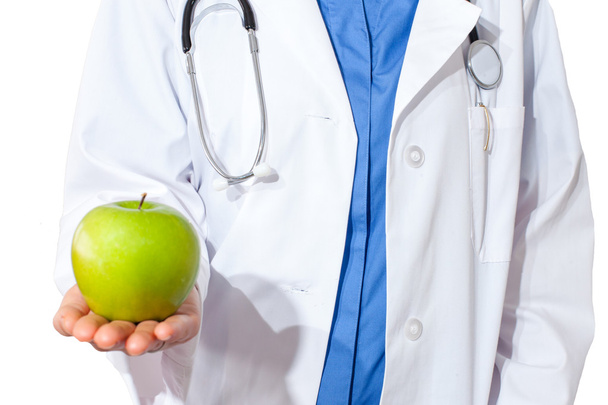Smiling nurse or young female doctor giving an green apple. - 写真・画像