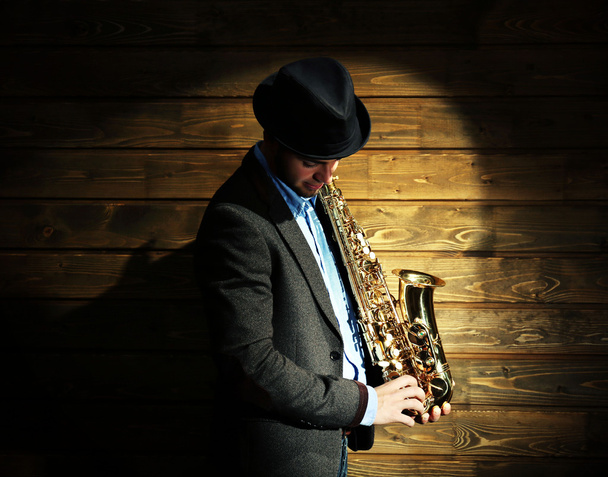Elegant saxophonist plays jazz on wooden background - Photo, Image