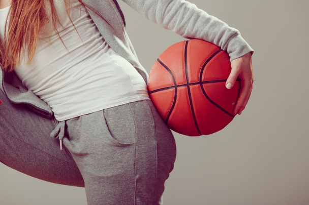 Sporty teen girl holding basketball with one hand. - Fotó, kép