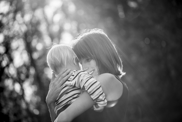 Black and white image of a happy smiling young mother hugging he - Foto, afbeelding