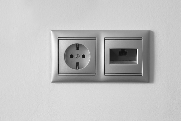 Toma de corriente eléctrica y Ethernet en una pared blanca texturizada
 - Foto, imagen