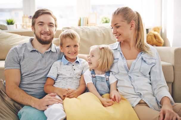 сім'я в повсякденному одязі, що сидить на дивані
 - Фото, зображення