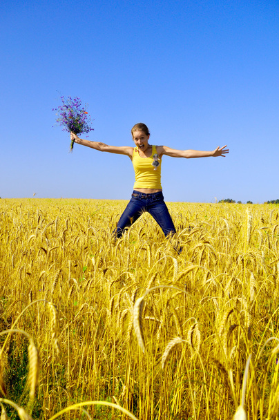 Όμορφο χαμογελαστό κορίτσι πηδά στο χρυσό πεδίο - Φωτογραφία, εικόνα
