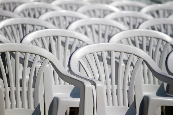 Aligned white plastic chairs - Foto, afbeelding