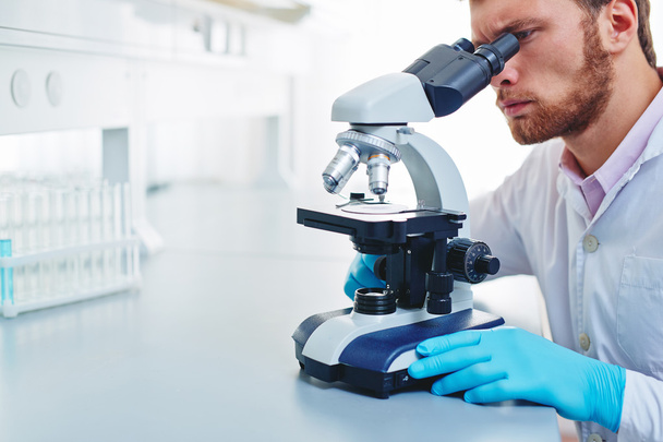 hombre estudiando la sustancia microbiológica en el microscopio
 - Foto, imagen
