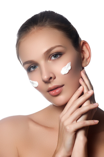 Skin care lady putting face cream. Attractive brunette girl on white background. Beautiful face of young woman with cosmetic cream on a cheek. Skin care concept. Skincare products - Фото, зображення