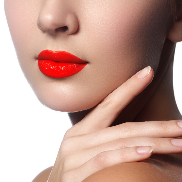 Close-up shot of woman lips with glossy red lipstick. Glamour red lips make-up, purity skin. Retro beauty style. Beautiful model girl with beauty makeup, red lips, perfect fresh skin. Youth and Skin Care Concept - 写真・画像