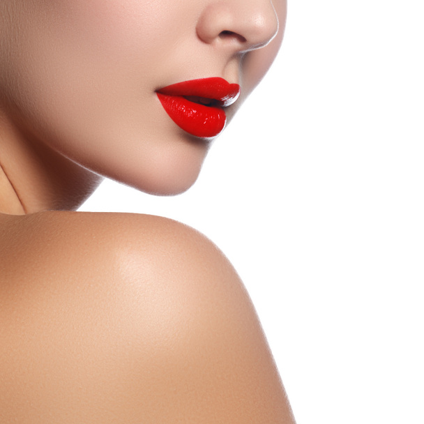 Close-up shot of woman lips with glossy red lipstick. Glamour red lips make-up, purity skin. Retro beauty style. Beautiful model girl with beauty makeup, red lips, perfect fresh skin. Youth and Skin Care Concept - 写真・画像