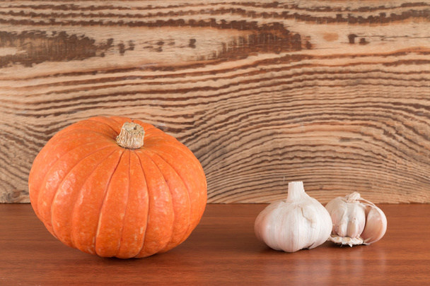 orange pumpkin and garlic on a wooden table - Fotó, kép