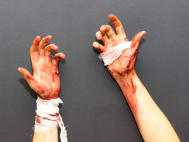 bloodied female hands tied with a bandage stained with blood on a gray background to the theme of Halloween - Foto, imagen