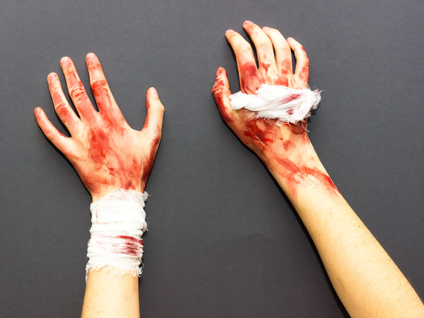 manos femeninas ensangrentadas atadas con un vendaje manchado de sangre sobre un fondo gris con el tema de Halloween
 - Foto, imagen