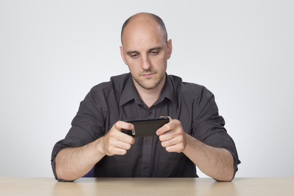 Man sat at desk playing on phone - Photo, Image