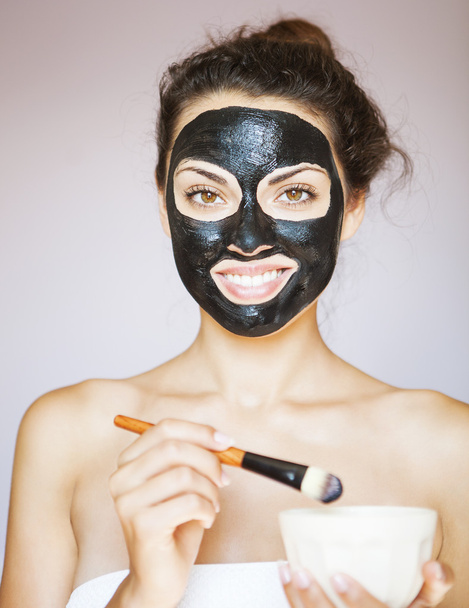 Νεαρή γυναίκα, εφαρμόζοντας μια μάσκα για το πρόσωπο του το θεραπευτικό blac - Φωτογραφία, εικόνα