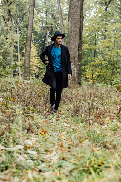 young man with black hat in forest - Foto, afbeelding