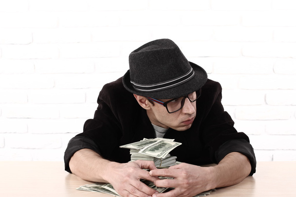 Емоційний чоловік в окулярах тримає пачки грошей
 - Фото, зображення