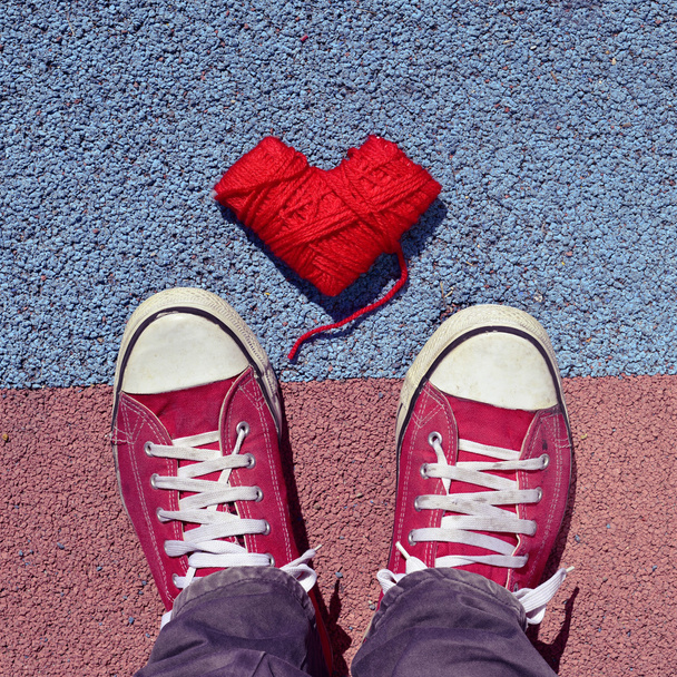άνθρωπος σε πάνινα παπούτσια και σχήμα καρδιάς σπείρας του νήματος στην άσφαλτο - Φωτογραφία, εικόνα