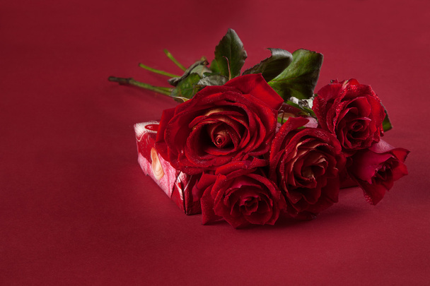 Bouquet of red roses and a gift for Valentine's Day on a red backgroun - Φωτογραφία, εικόνα