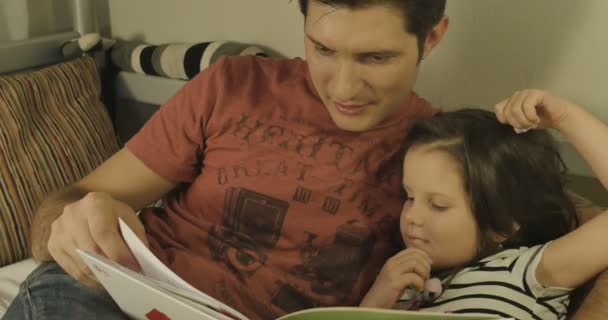 A father and daughter spend time together reading a book - Filmati, video