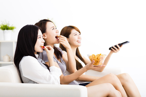 feliz grupo de mujeres jóvenes comiendo bocadillos y viendo la televisión
 - Foto, imagen
