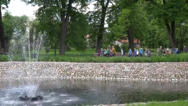 噴水と緑の公園で教師と子供の遠足旅行。4k - 映像、動画
