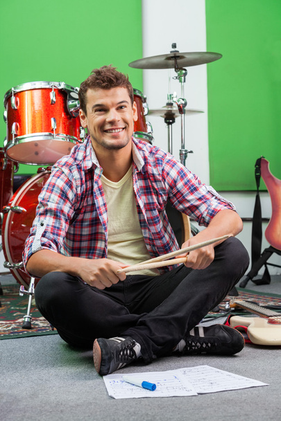 Male Drummer Holding Sticks While Sitting On Floor - Foto, immagini