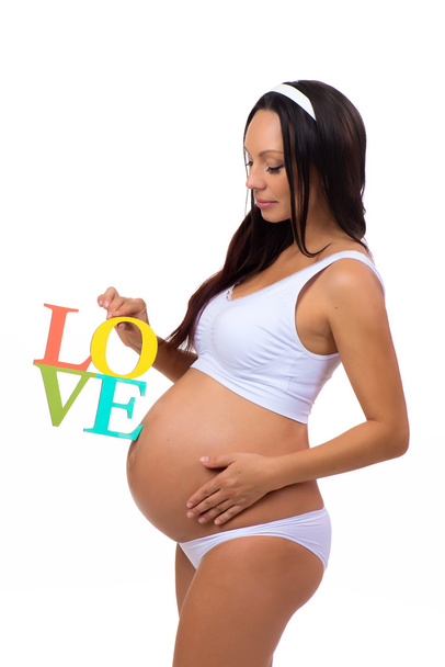 Label liefde in de handen van zwangere vrouw geïsoleerd op verticale witte achtergrond - Foto, afbeelding