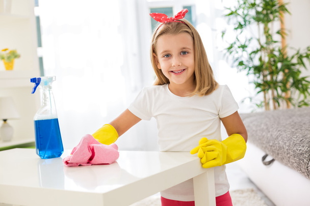 Adorable worth girl holding pom and cleaning a table at living r - Φωτογραφία, εικόνα
