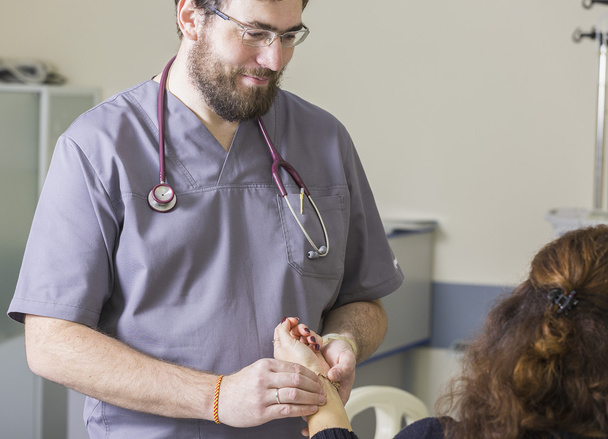 médico barbudo con gafas comprueba el pulso del paciente
 - Foto, imagen
