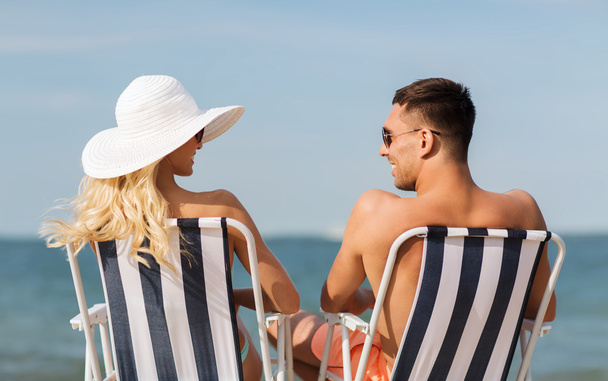 happy couple sunbathing in chairs on summer beach - Photo, Image