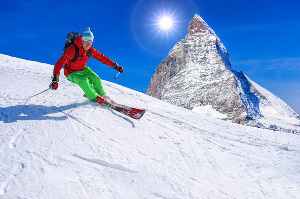 Skier skiing downhill against Matterhorn peak in Switzerland - Photo, Image