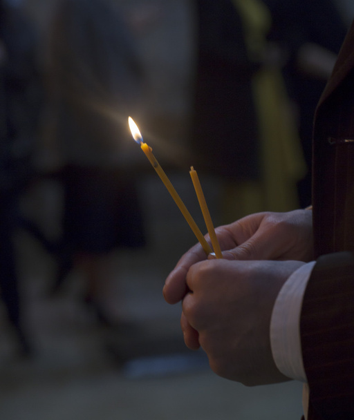Férfi kézi világító gyertyák egy templomban. ő gyertyák, a grúz egyház. Hosszú gyertyát csoport fekete háttér. - Fotó, kép