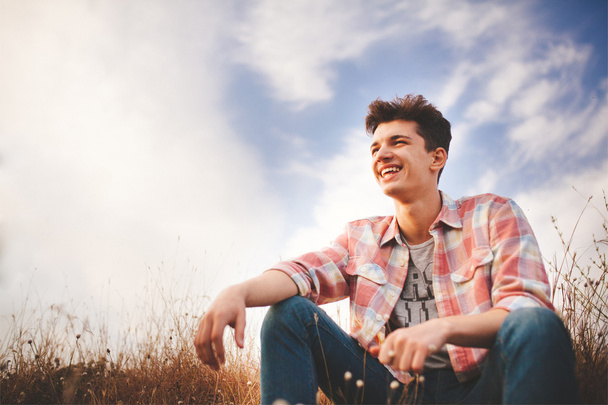 Smiling teenage boy wearing casual shirt outdoors - Фото, изображение